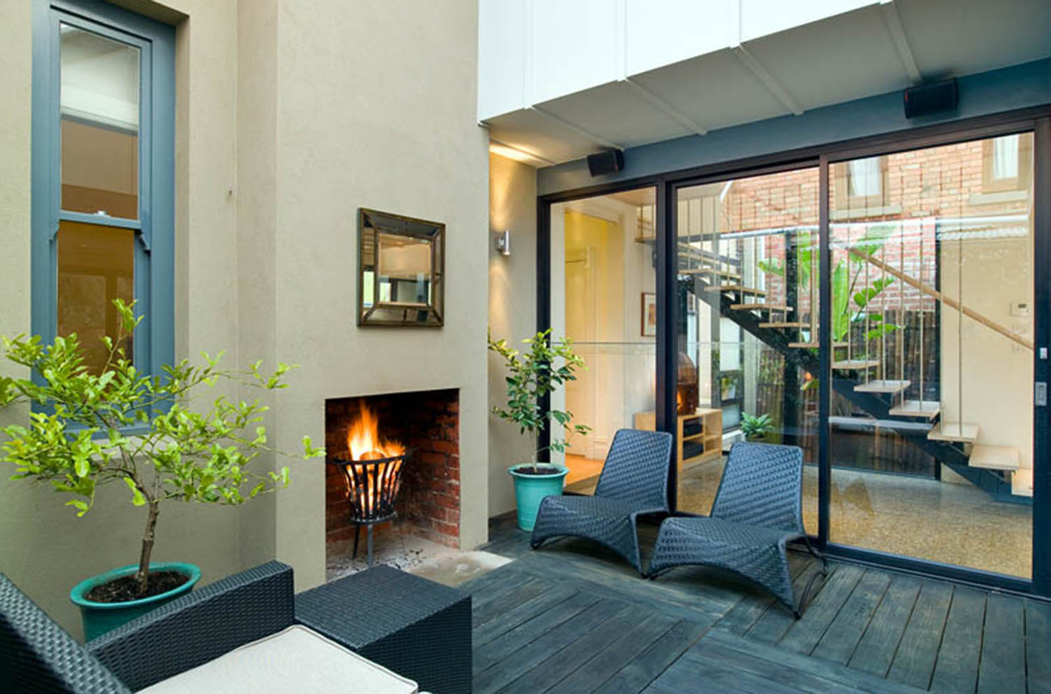 Australian house interiors, fireplace in the living area with a view of the stairs through the glass wall