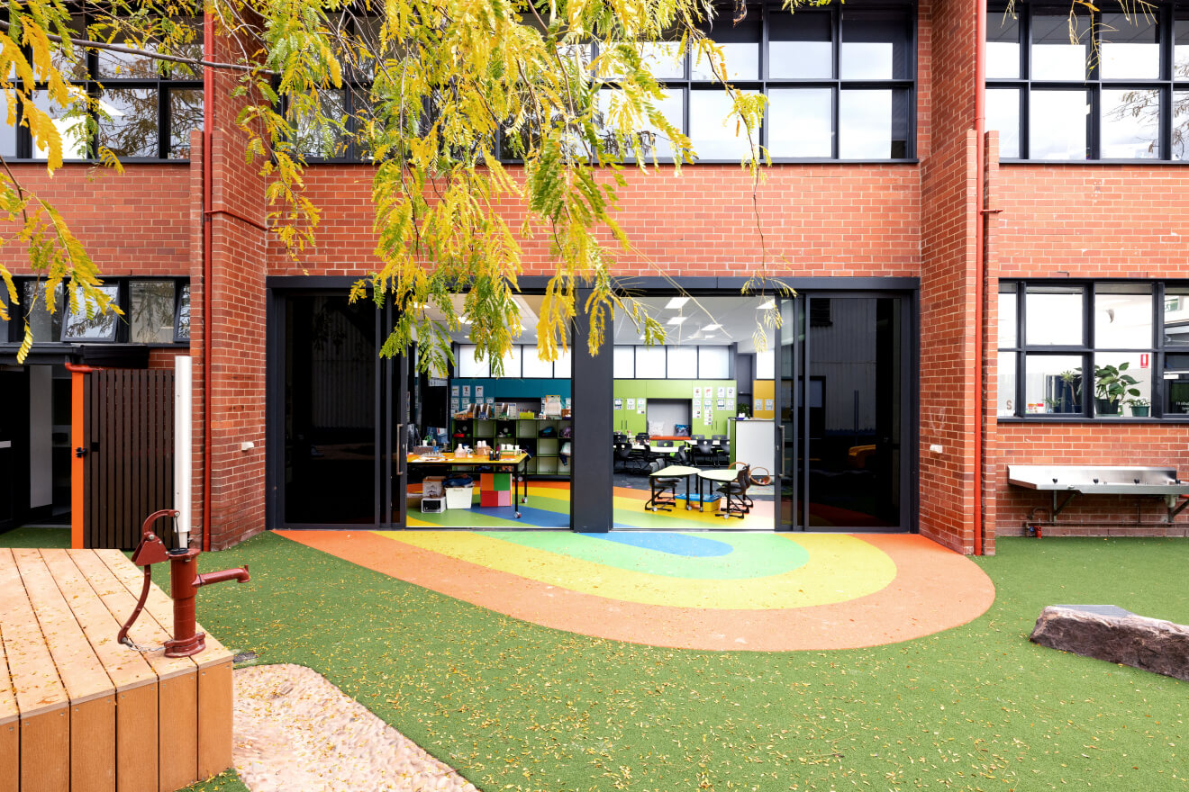 The front of Sacred Heart Primary School with trees and green rubber grass